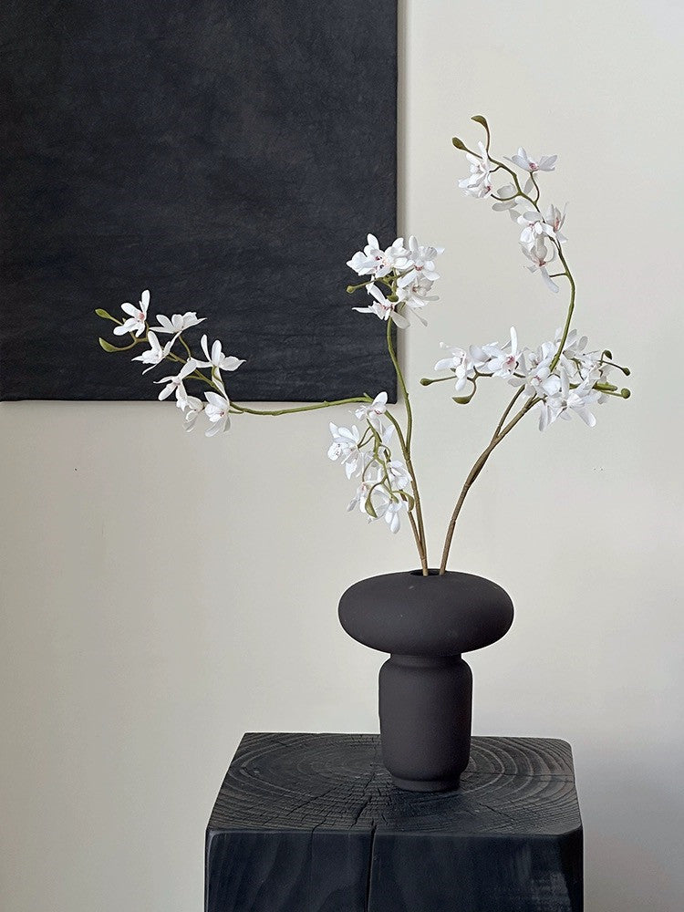 Mushroom shaped ceramic vase displayed with decorative branches on a table