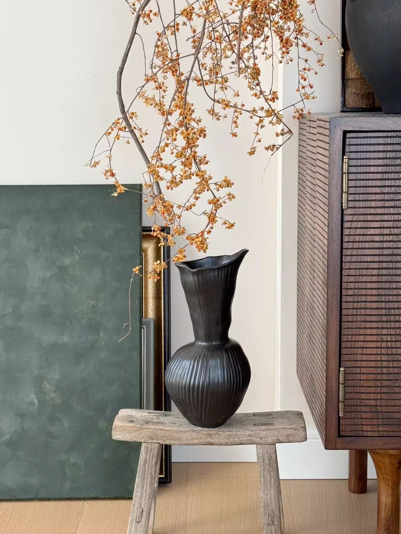 Ribbed gourd ceramic vase displayed with decorative branches indoors