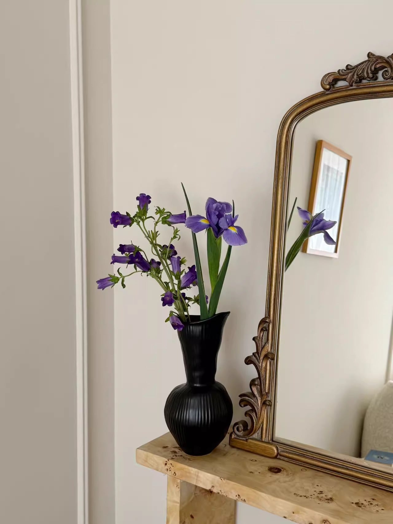 Ribbed gourd ceramic vase displayed with flowers near a mirror