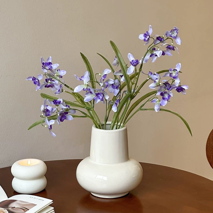 Rounded bulb ceramic vase displayed with decorative flowers indoors