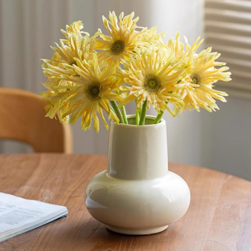 Rounded bulb ceramic vase with flowers displayed on a dining table