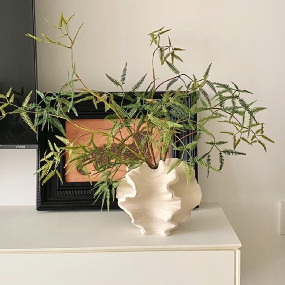 Ruffled wave ceramic vase displayed with decorative branches on a console
