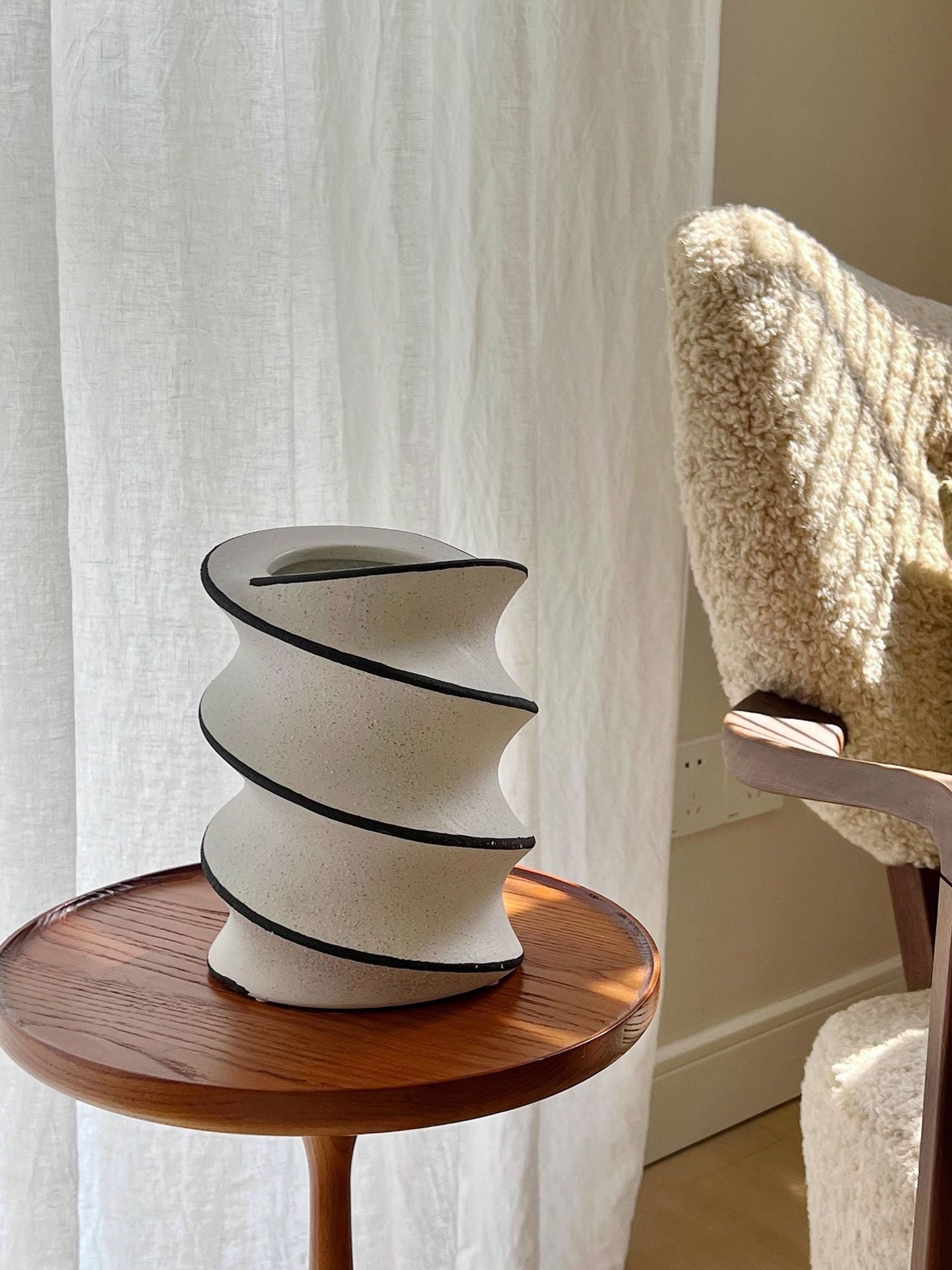 Spiral ceramic vase displayed on a wooden side table